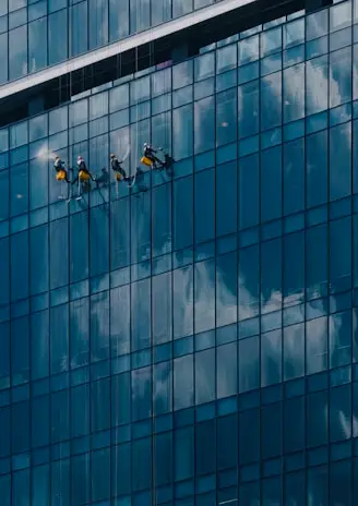 Rope cleaning technicians hanging to a large and tall glass building