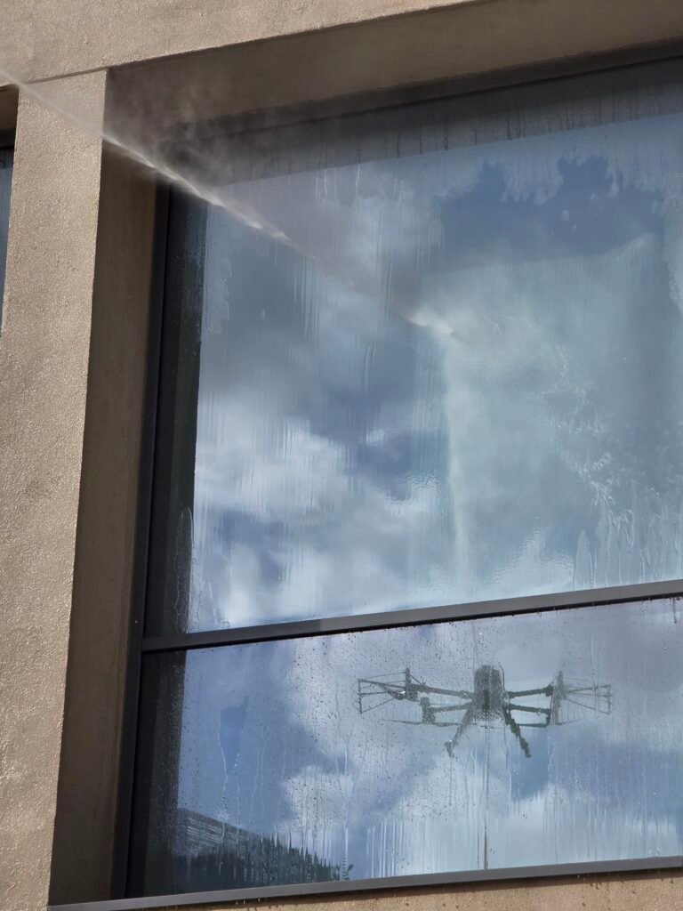 DRONICLE window cleaning using drone in Dubai. The drone can be seen through the reflection in the glass.