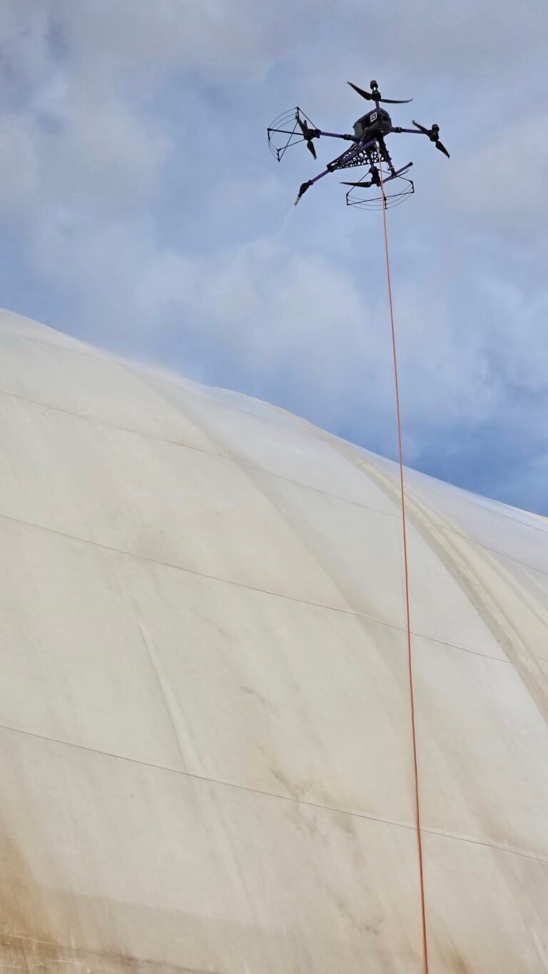 DRONICLE’s drone precision-cleaning a PVC tarpaulin in Dubai, showcasing advanced drone technology removing dirt and stains for a spotless, eco-friendly result.