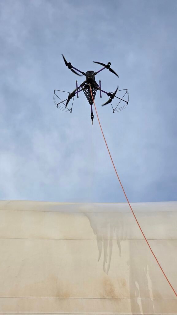 Close-up of DRONICLE’s drone precision-cleaning a PVC tarpaulin in Dubai, showcasing advanced drone technology removing dirt and stains for a spotless, eco-friendly result.