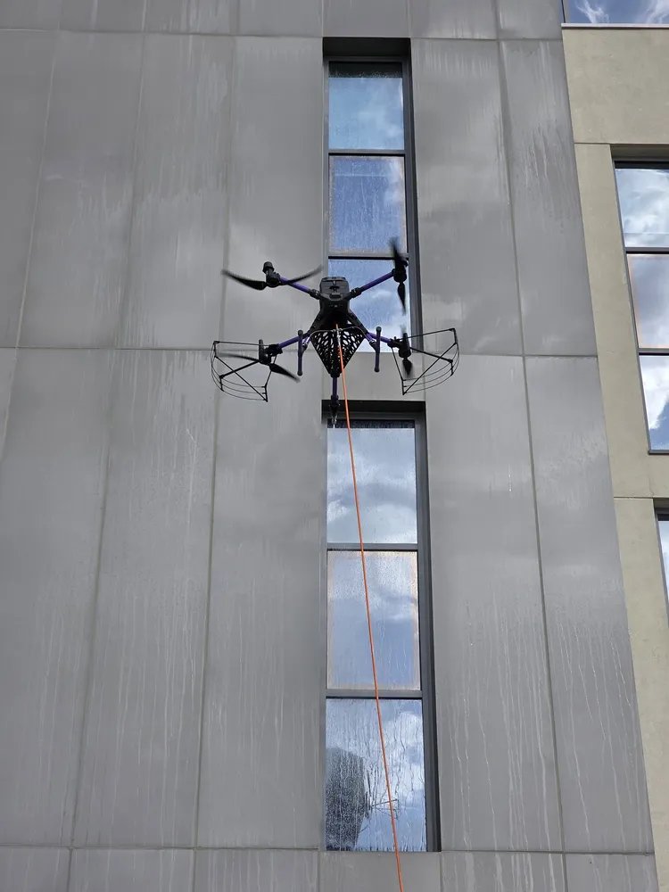 DRONICLE's drone cleaning the facade of a school, removing the dirt acumulated.