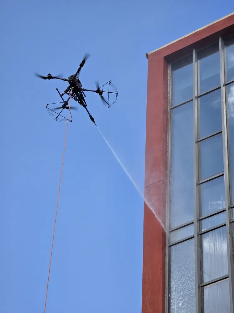 DRONICLE's drone cleaning the facade of a school, removing the dirt acumulated.