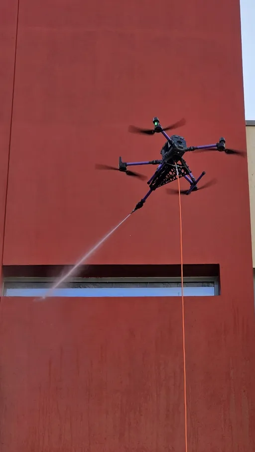 DRONICLE's drone cleaning the facade of a school, removing the dirt acumulated.